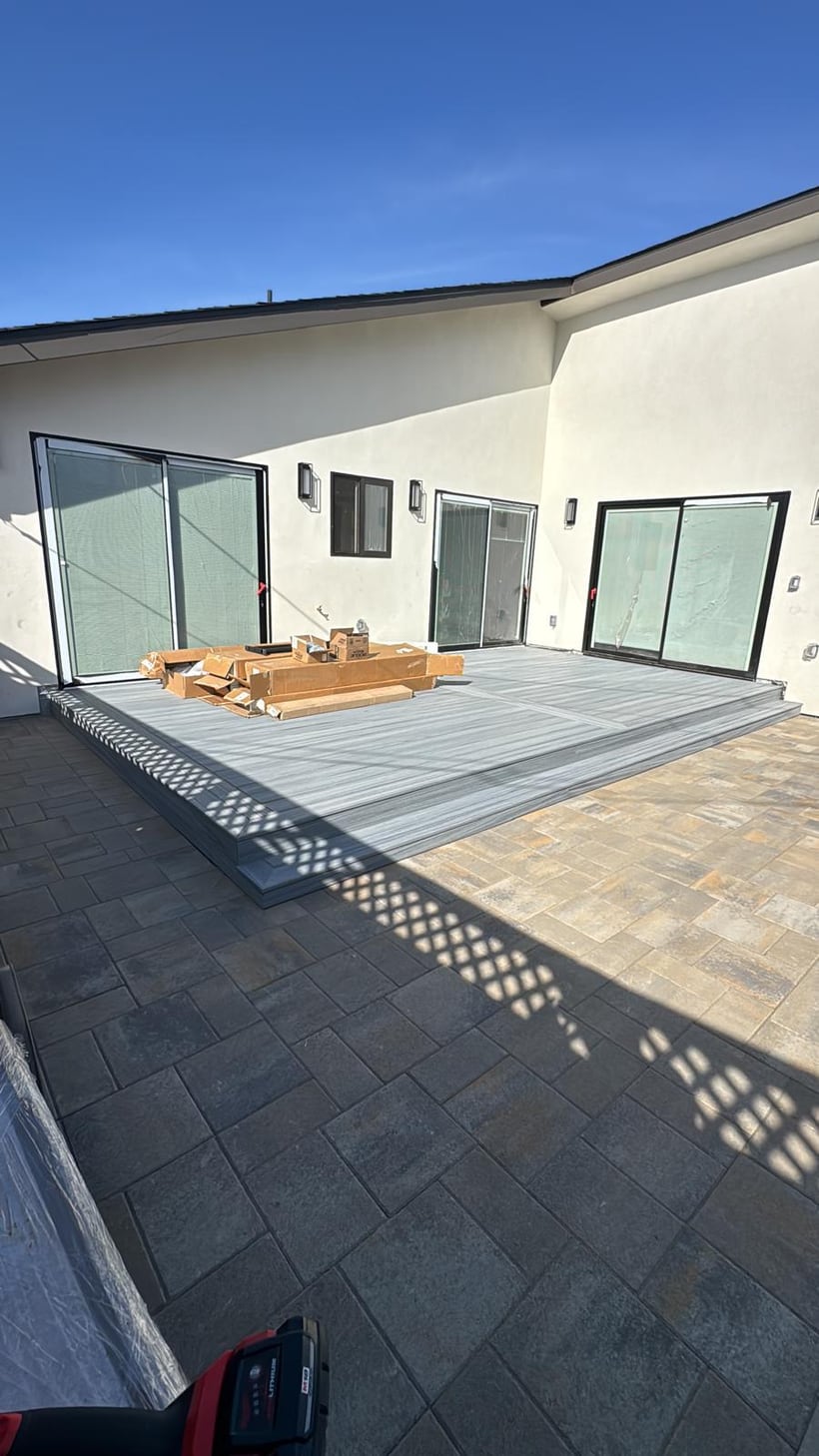 Backyard composite deck surface being prepared near sliding patio doors
